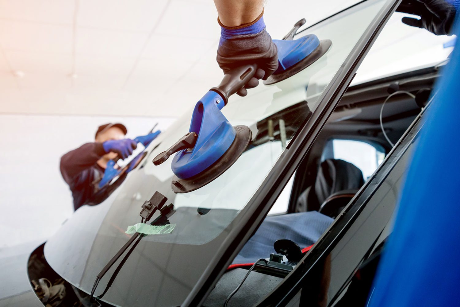 An image of a new windscreen being fitted by two members of staff in the autoglass industry