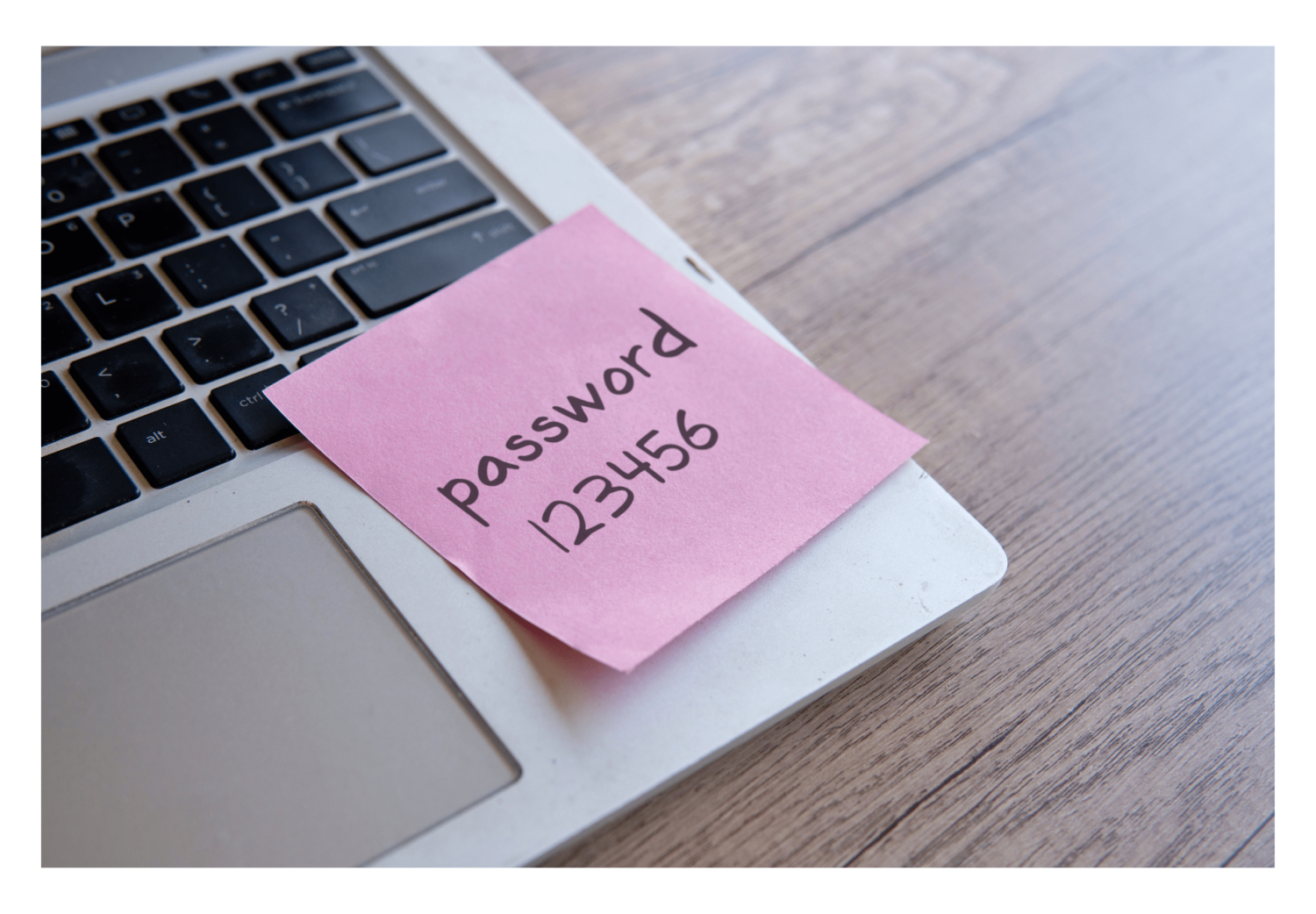 An image showing a post-it note attached to a laptop depicting a password written down