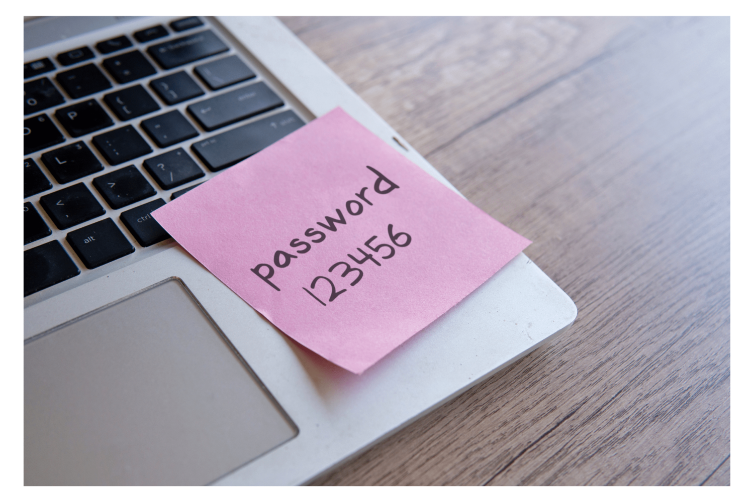 An image showing a post-it note attached to a laptop depicting a password written down